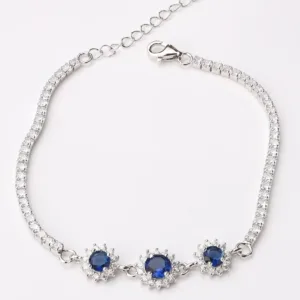 Elegant silver tennis bracelet with three sapphire flowers surrounded by diamonds, adjustable chain clasp, perfect for special occasions