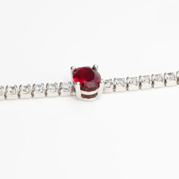 Detailed view of a sterling silver tennis bracelet with cubic zirconia stones and a prominent oval-cut ruby-red gemstone in the center