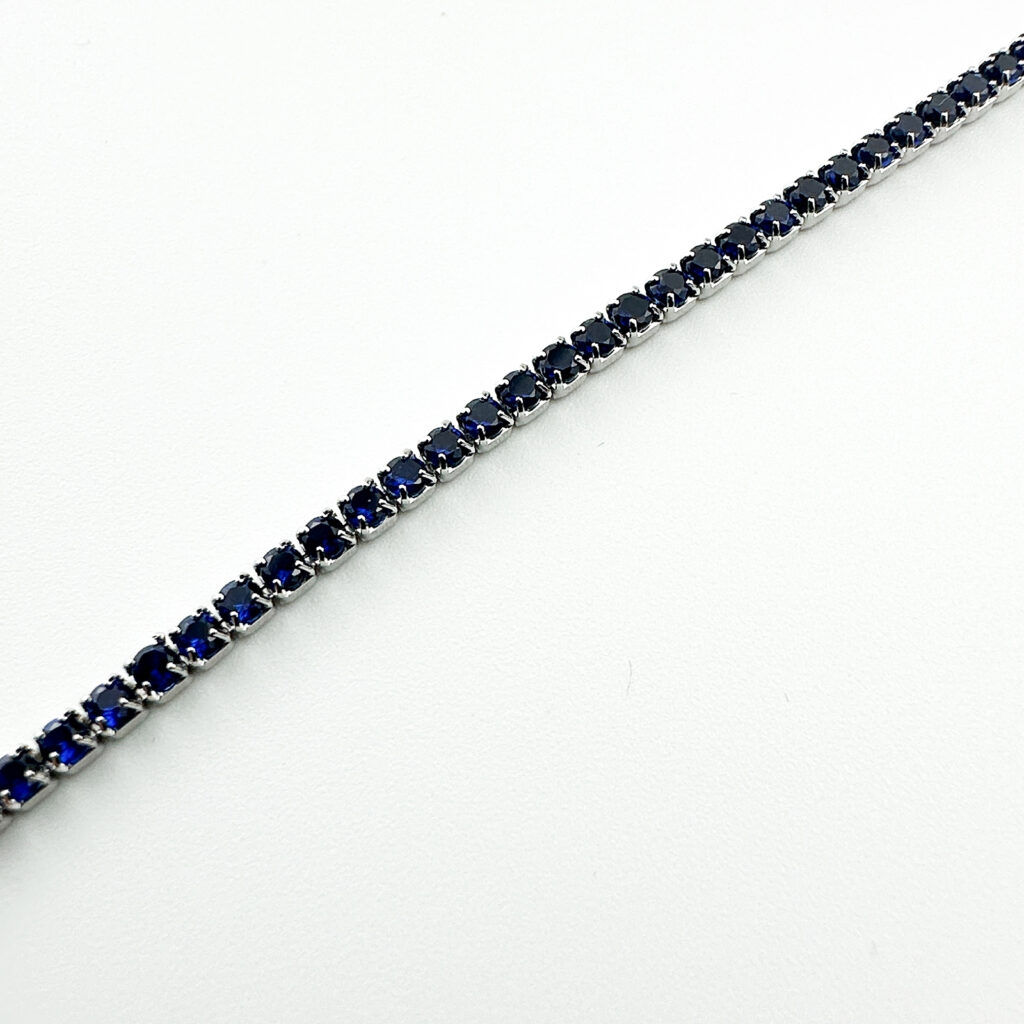 A delicate sterling silver tennis bracelet adorned with sparkling blue gemstones.