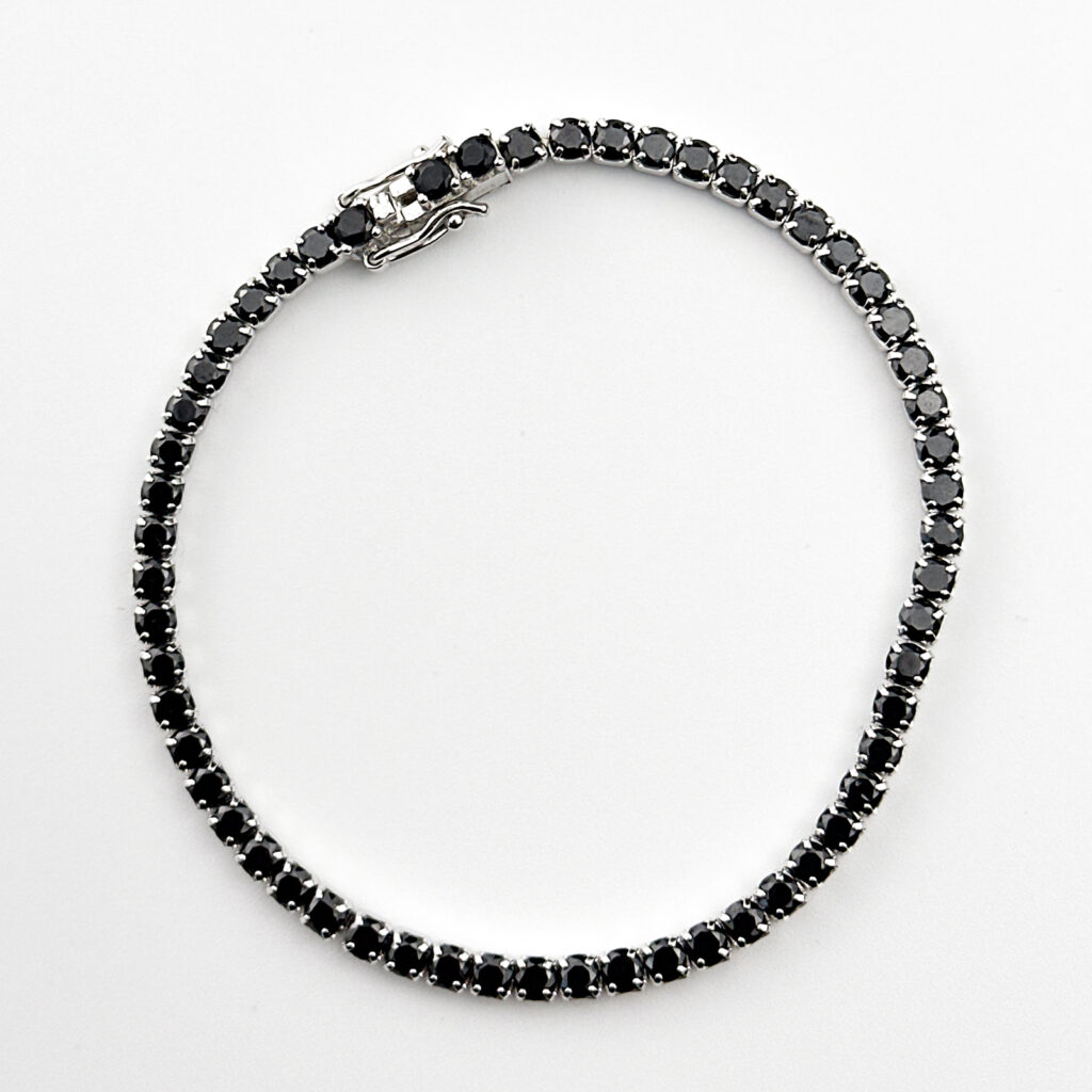 A delicate sterling silver tennis bracelet featuring sparkling black gemstones.