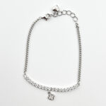 A silver tennis bracelet with cubic zirconia stones and a flower-shaped charm.