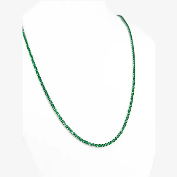 A silver tennis necklace with small, square-cut emerald gemstones.