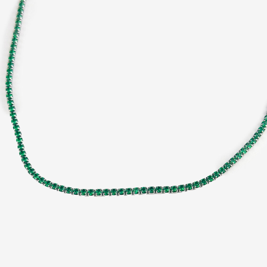 A silver tennis necklace with small, square-cut emerald gemstones.