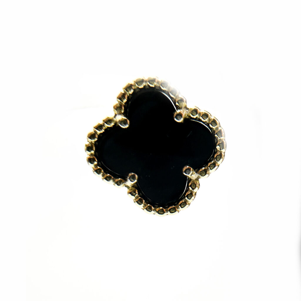 A single earring in the shape of a four-leaf clover with a black onyx center and a gold beaded border.