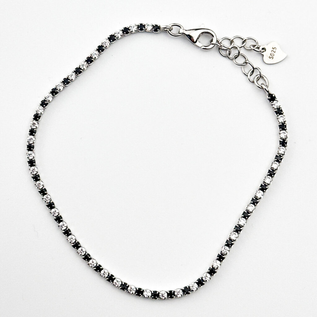 A sterling silver tennis bracelet with alternating black and white cubic zirconia stones.