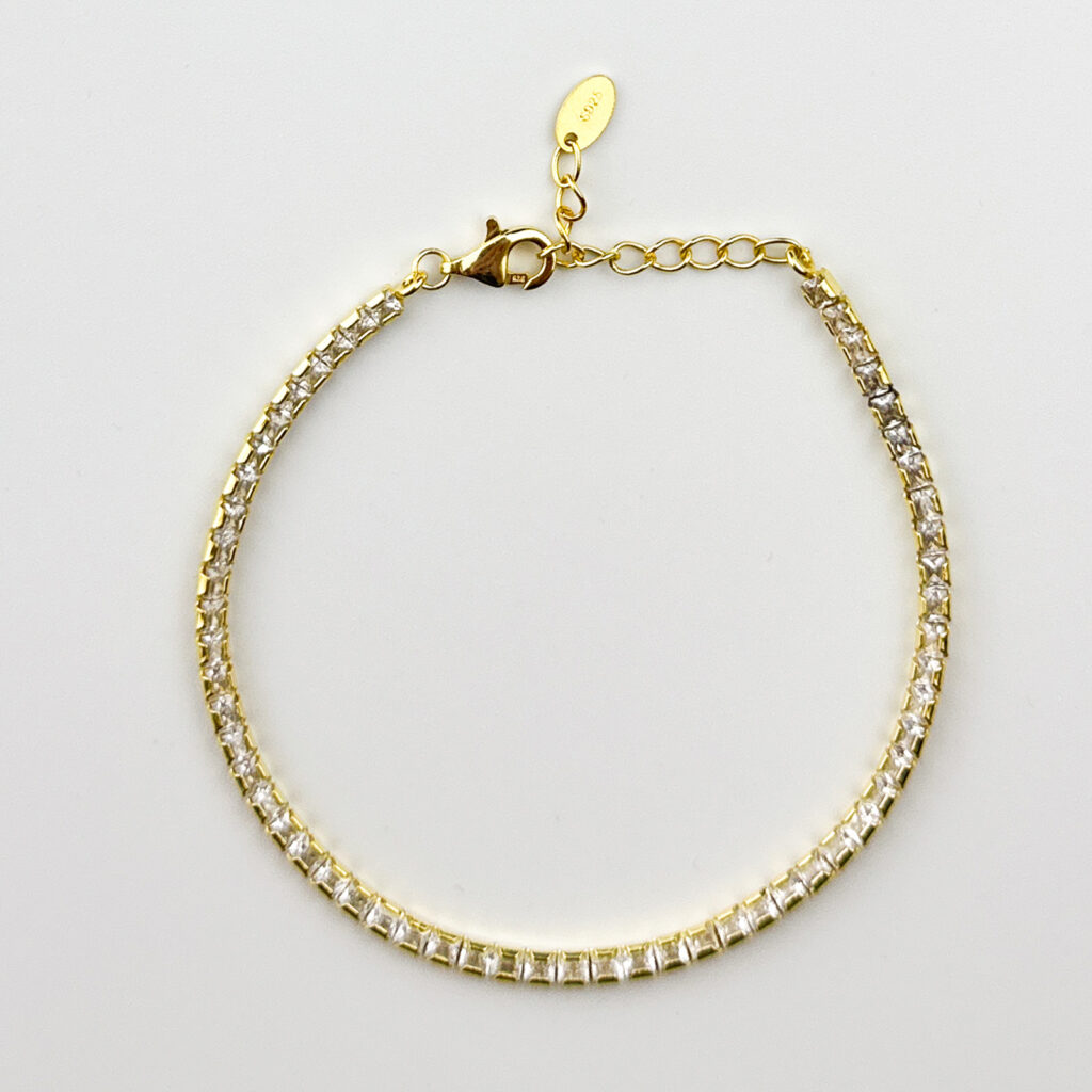 A gold tennis bracelet with square cubic zirconia stones.