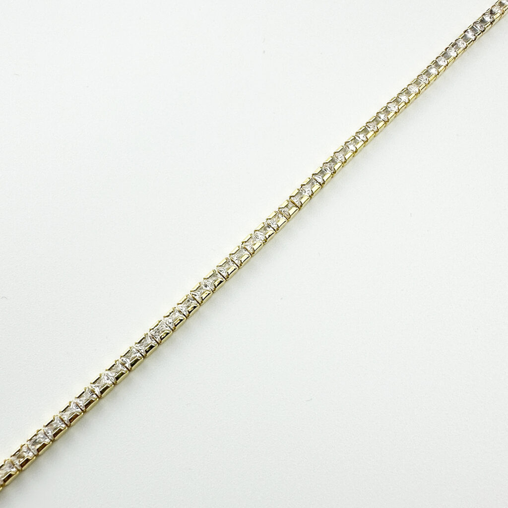 A gold tennis bracelet featuring a continuous line of square-cut clear gemstones.