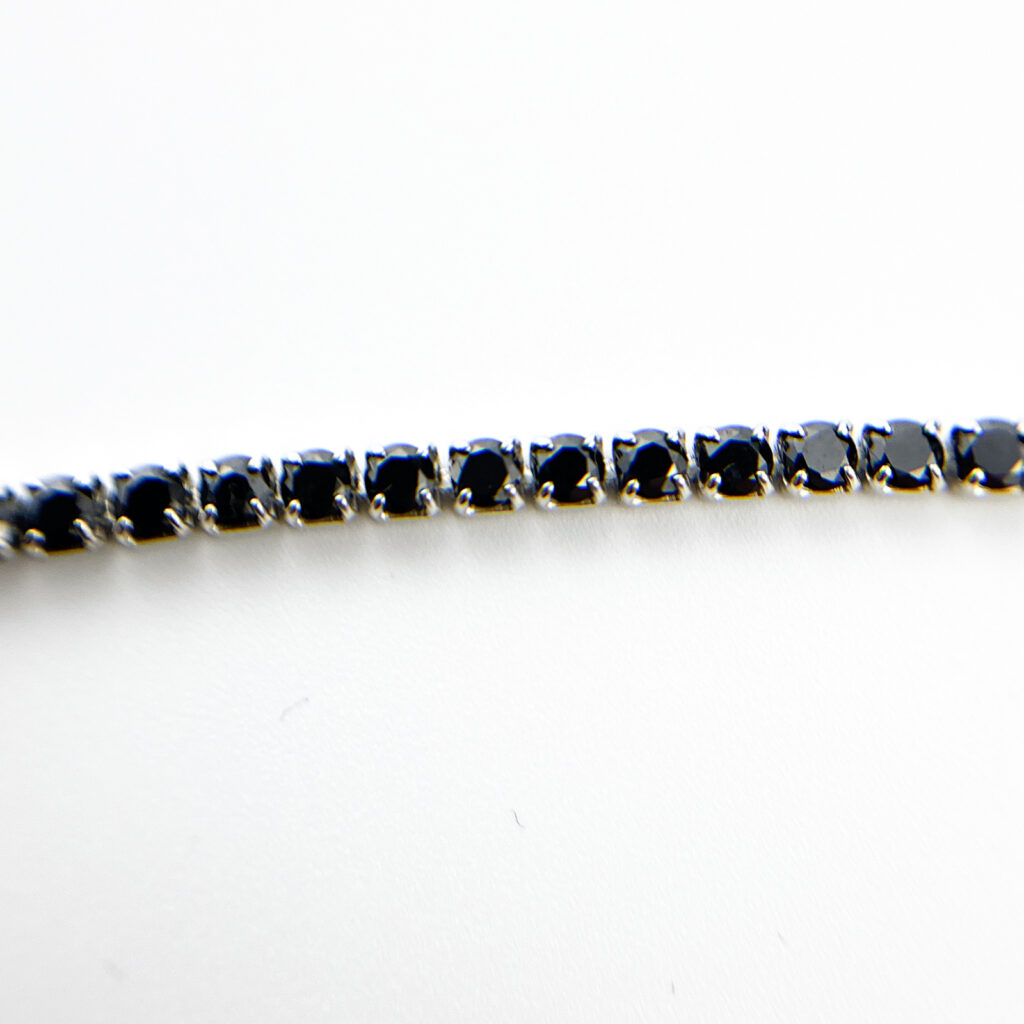 Close-up of a tennis bracelet with black stones set in a silver band.