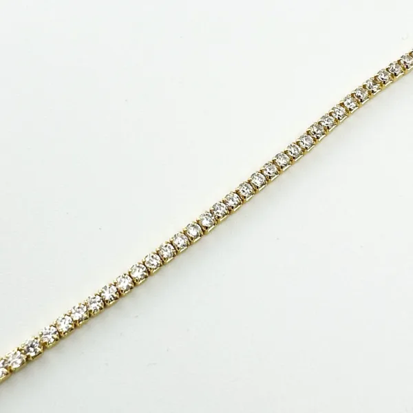 A gold tennis bracelet with round brilliant-cut diamonds on a white background.