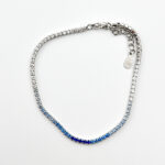 A sterling silver tennis bracelet with a gradient of blue cubic zirconia stones, transitioning from clear to dark blue