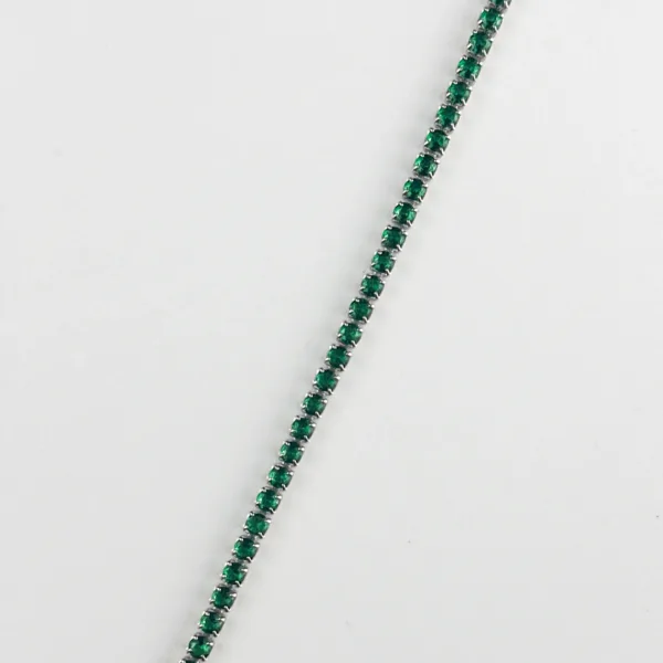 A silver tennis bracelet with small, square-cut emerald gemstones.