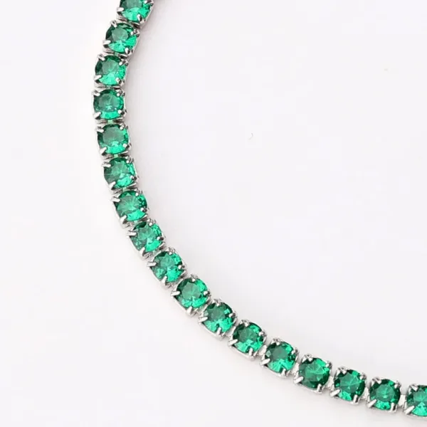 Close-up of emerald tennis bracelet showing vibrant green round-cut gemstones in prong settings, set in silver