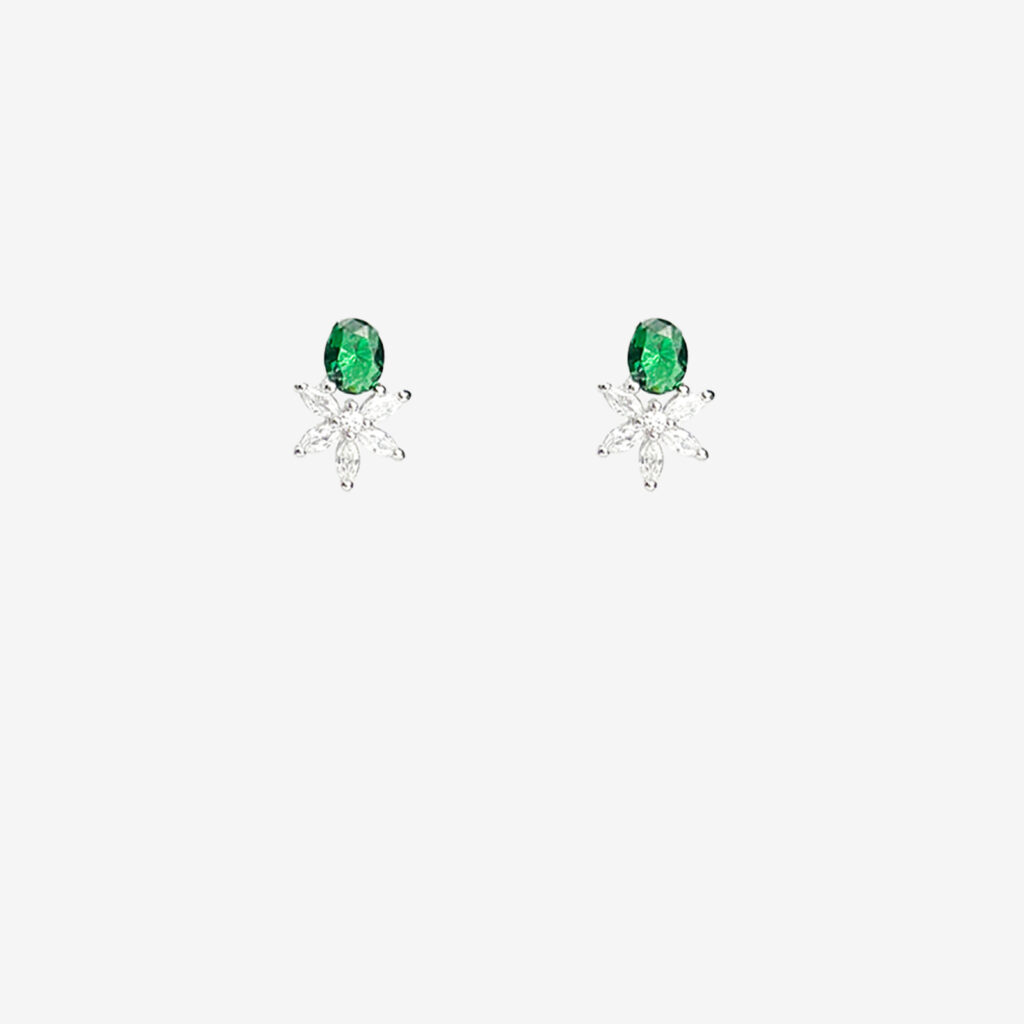 A pair of silver stud earrings with a green oval gemstone set above a cluster of clear gemstones arranged in a floral pattern.