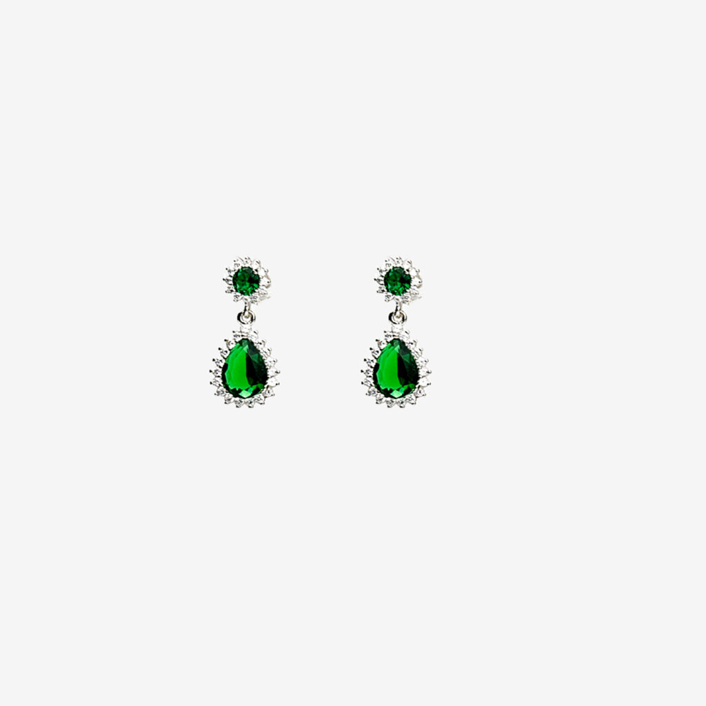 A pair of silver dangle earrings with a teardrop-shaped emerald green gemstone and a smaller round emerald gemstone, both surrounded by a halo of clear gemstones.