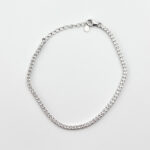 A silver tennis bracelet with small cubic zirconia stones on a white background.