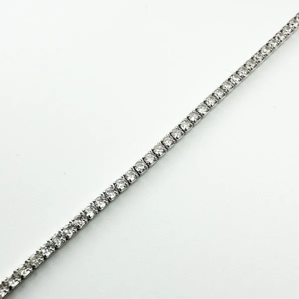 A delicate silver tennis bracelet with small, sparkling clear stones.