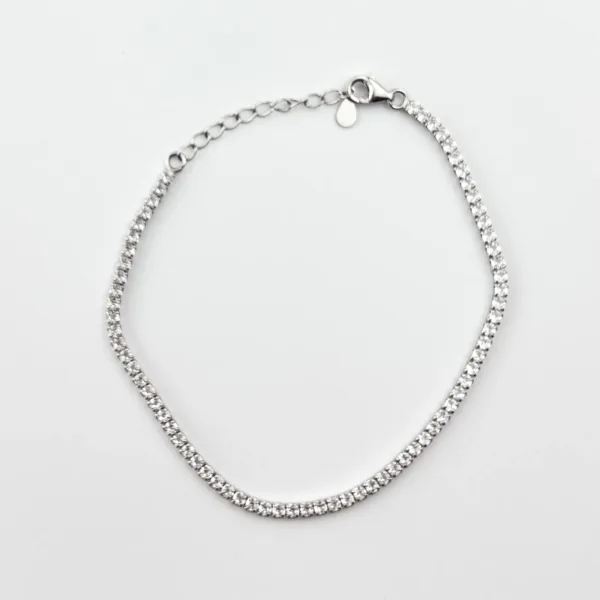 A silver tennis bracelet with small cubic zirconia stones on a white background.