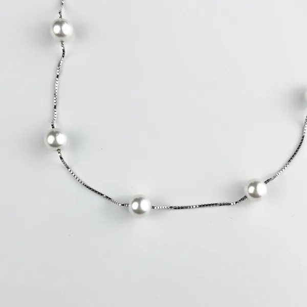 A silver box chain necklace with evenly spaced white pearls displayed against a white background.