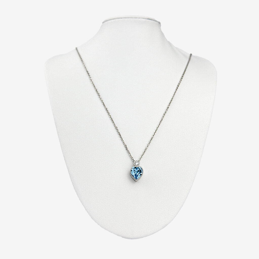 A silver chain necklace with a square-cut blue topaz pendant surrounded by smaller diamonds, displayed on a white mannequin bust.