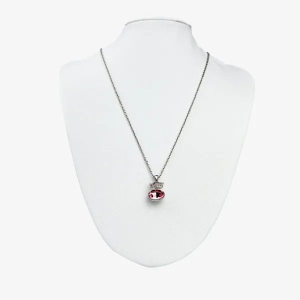 A silver chain necklace with a red oval pendant and a small rectangular accent, both adorned with clear gemstones. Displayed on a white mannequin bust.