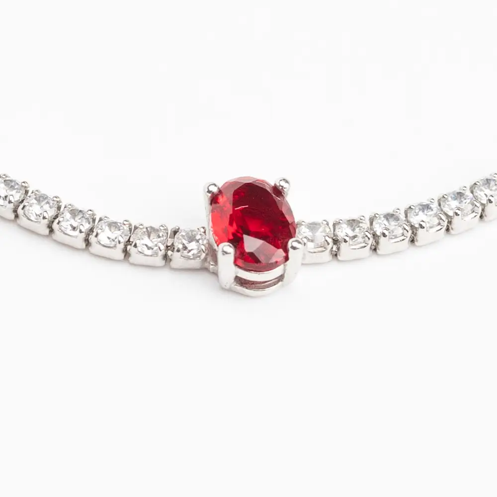 Detailed view of a sterling silver tennis bracelet with cubic zirconia stones and a prominent oval-cut ruby-red gemstone in the center