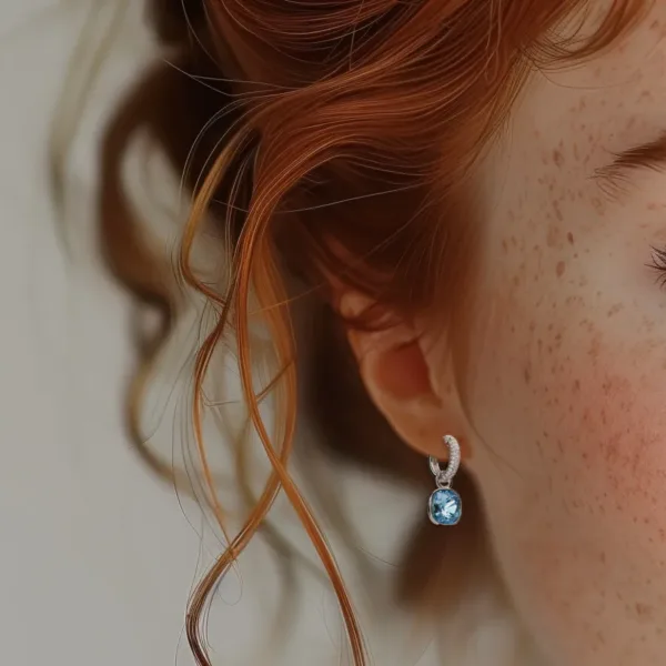 Elegant blue topaz drop earring on redhead woman, showcasing sterling silver and diamond accents