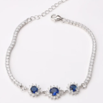 Sterling silver tennis bracelet with sapphire crystals and floral clasp, top view
