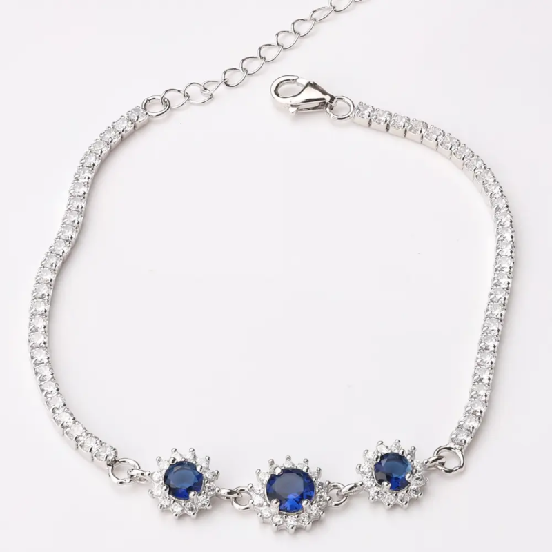 Sterling silver tennis bracelet with sapphire crystals and floral clasp, top view